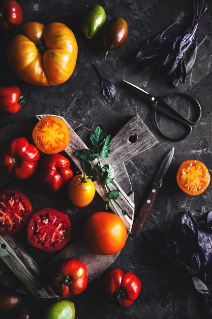 Samenstelling met heerlijke tomaten, houten plank en producten op grijze achtergrond, gezonde voeding, groenten