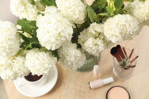 Samenstelling met hortensia bloemen, kopje koffie en cosmetica. Lente plant