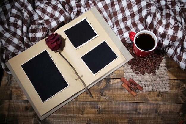 Samenstelling met koffiekopje plaid en fotoalbum op houten achtergrond