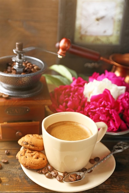 Samenstelling met koffiemolen kopje koffie en peony bloemen op houten achtergrond