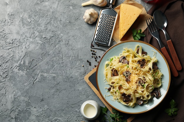 Samenstelling met plaat van smakelijke pasta en ingrediënten voor het koken op grijze muur