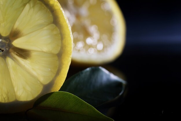 Foto samenstelling met plakjes sinaasappel en grapefruit op een zwarte achtergrond. een schijfje sinaasappel met achtergrondverlichting op een zwarte achtergrond met waterdruppels. sappige sinaasappel op een tafel.