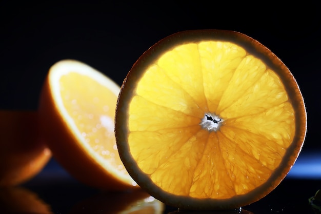 Samenstelling met plakjes sinaasappel en grapefruit op een zwarte achtergrond. Een schijfje sinaasappel met achtergrondverlichting op een zwarte achtergrond met waterdruppels. Sappige sinaasappel op een tafel.