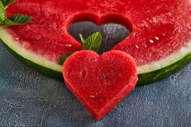 Samenstelling met rijpe watermeloen, muntblaadjes en een hart gesneden in een schijfje watermeloen. Concept voor Valentijnsdag