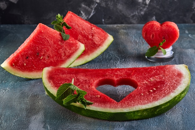 Samenstelling met rijpe watermeloen, muntblaadjes en een hart gesneden in een schijfje watermeloen.