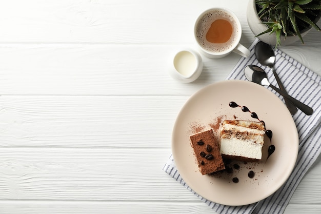 Samenstelling met smakelijke tiramisu en cacaodrank op witte houten tafel.