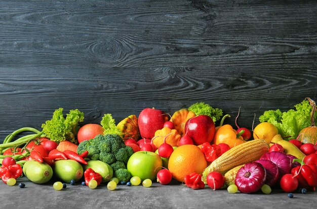 Samenstelling met verschillende groenten en fruit op tafel tegen donkere houten achtergrond