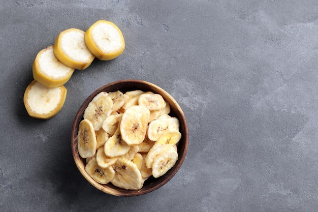 Samenstelling met zoete plakjes banaan en verse banaan op tafel, bovenaanzicht met ruimte voor tekst. Gedroogd fruit als gezond tussendoortje