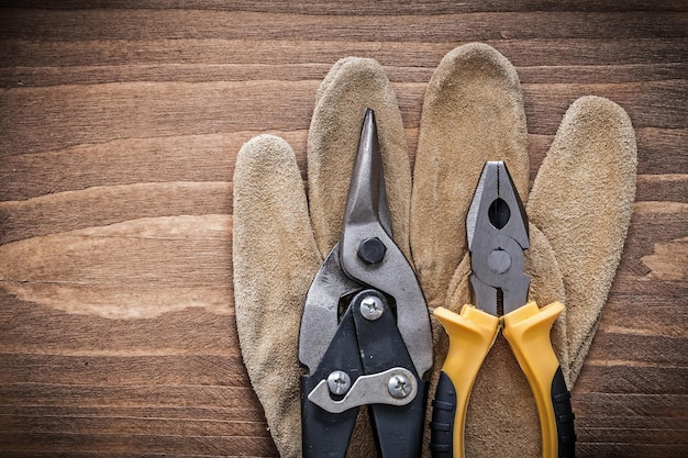 Samenstelling stalen kniptang veiligheidshandschoenen op houten plank