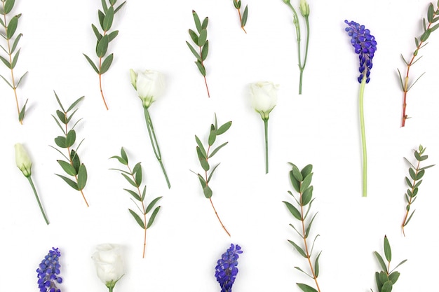 Samenstelling van bloemen. een patroon van rozen, greens en wilde bloemen op een witte achtergrond. plat lag, bovenaanzicht.