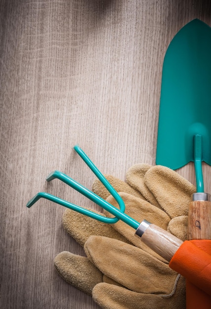 Samenstelling van de handspade van leer werkende handschoenen en het tuinieren hark op het houten concept van de raadslandbouw