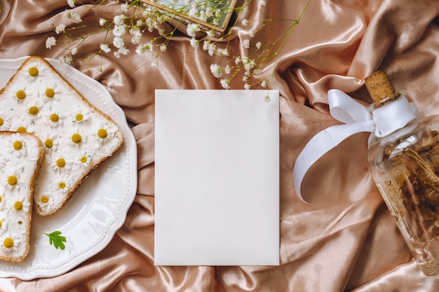 Samenstelling van de lente, wit blanco papier, toast brood sandwich met kamille bloemen in een witte plaat