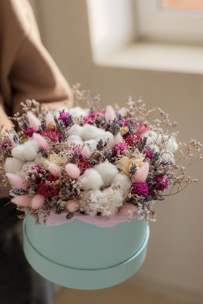 Samenstelling van droogbloemen in een ronde doos met katoen lagurus gelik limonium korenaren