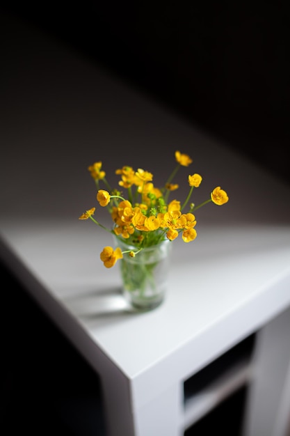 Samenstelling van felgele wilde bloemen in een glazen beker