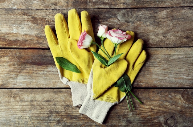 Samenstelling van gevoelige bloesem en gele handschoenen van de tuinman op houten achtergrond