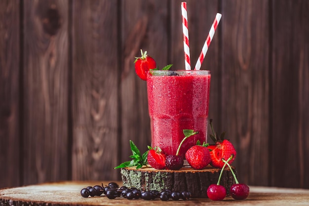 Samenstelling van glas met verse karmozijnrode smoothie met zomerbessen op houten achtergrond Lekker eten