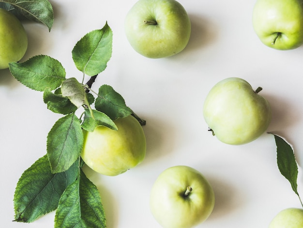 Samenstelling van groene appels en bladeren op een witte achtergrond. wallpaper van fruit. bovenaanzicht, plat leggen.