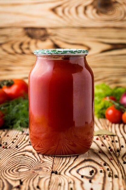 Samenstelling van ingeblikt tomatensap in pot en ingrediënten op houten achtergrond