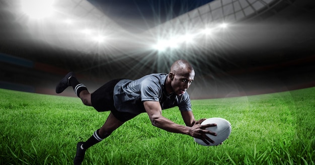 Samenstelling van mannelijke rugbyspeler duiken met bal op rugbyveld