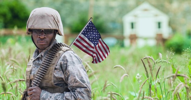 Samenstelling van mannelijke soldaat met wuivende Amerikaanse vlag, tegen landelijke omgeving