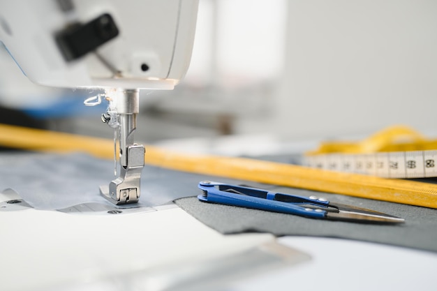 Samenstelling van naaigarenschaar en meetlint op een witte tafel Concept van een kledingontwerper