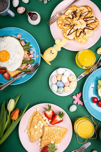 Samenstelling van pasen met ontbijt plat lag met roerei bagels, tulpen, pannenkoeken, brood toast met gebakken ei en groene asperges, gekleurde kwarteleitjes. bovenaanzicht