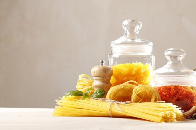 Samenstelling van rauwe verschillende pasta, fettuccine, boekweitpasta met plaats voor tekst op een witte houten achtergrond. Bovenaanzicht.