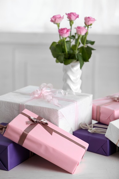 Samenstelling van schattige geschenkdozen en rozen op witte tafel