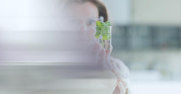 Samenstelling van vrouwelijke wetenschapper die beker met plant vasthoudt in laboratorium met bewegingsonscherpte