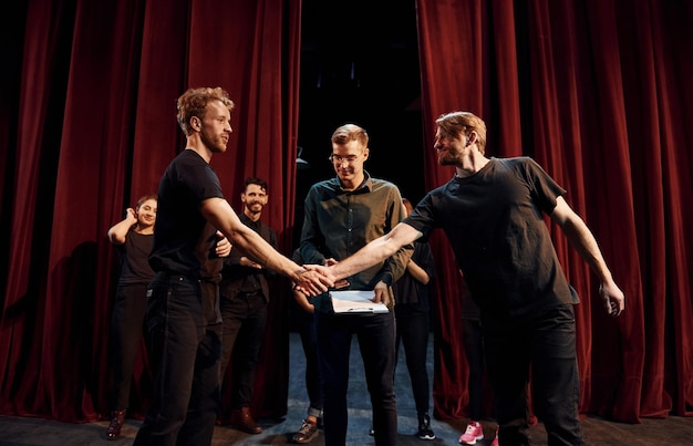 Samenwerkende groep acteurs in donkere kleding op een repetitie in het theater