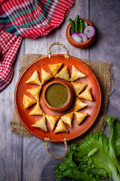 Samosa su un piatto con salsa e pomodori vista orizzontale dall'alto in stile rustico