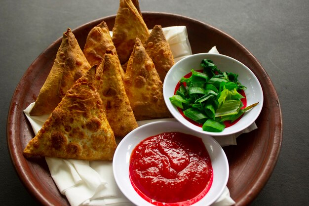 Samosa samsa or somsa are triangular fried pastries or pastri served with tomato sauce and leek slice on black background