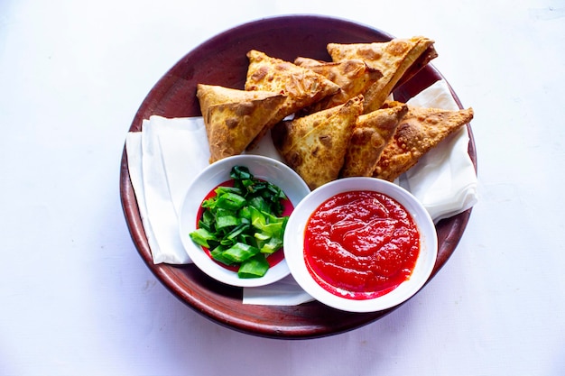Samosa samsa or somsa are triangular fried pastries or pastri served with tomato sauce and leek slice on black background