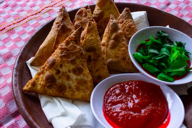 Samosa samsa or somsa are triangular fried pastries or pastri served with tomato sauce and leek slice on black background
