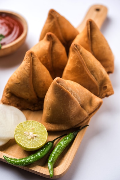 Samosa snack served with tomato ketchup and mint chutney