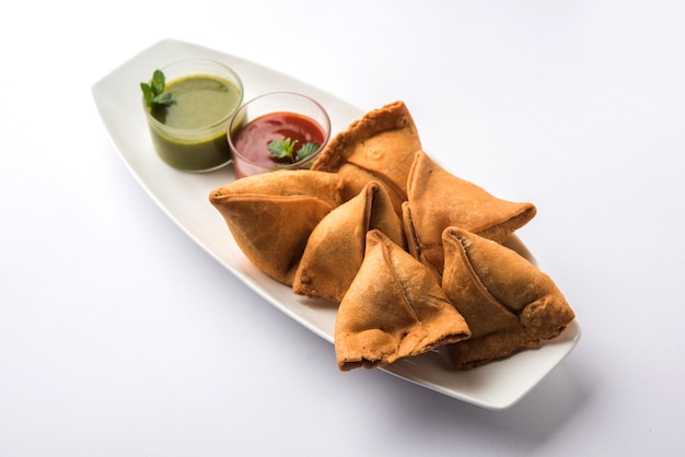 Samosa snack served with tomato ketchup and mint chutney