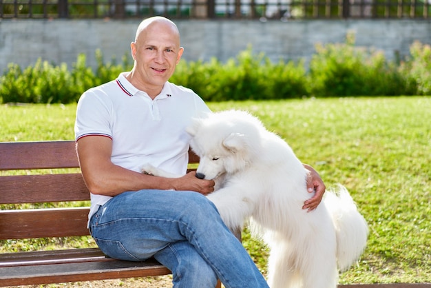 Foto cane samoiedo con il suo proprietario al parco che giocano insieme