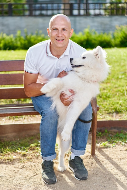 Foto cane samoiedo con il suo proprietario al parco che giocano insieme