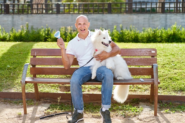 Foto cane samoiedo con il suo proprietario al parco che giocano insieme