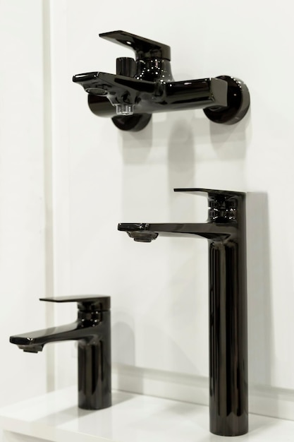 Samples of black faucets against a white wall Exhibition of finishing materials Vertical