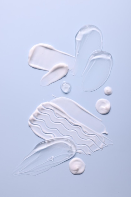 samples of face cream on light blue background top view