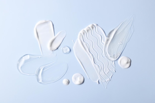 samples of face cream on light blue background top view