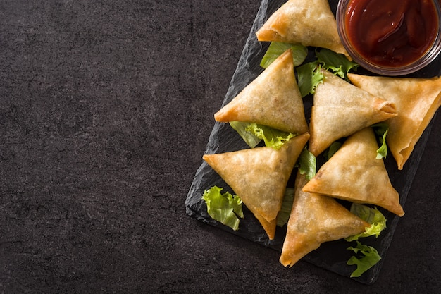 Samsa of samosas met vlees en groenten op zwart. copyspace