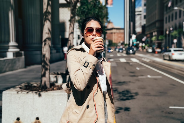 san francisco city commute waiting taxi cab. Asian businesswoman walking to work in the morning commuting drinking coffee cup on street with cars in the background banner. People commuters lifestyle.