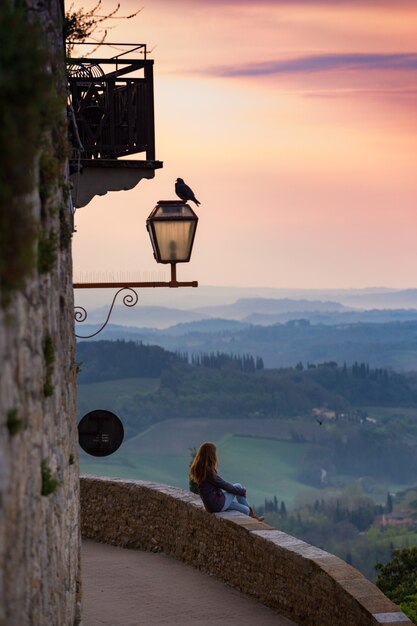 San Gimignano. girl looking at the tuscanian landscape with the hills and cypresses at dawn