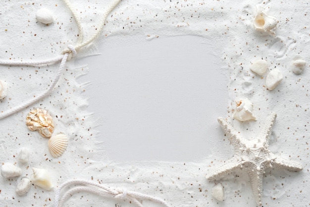 Sand background with seashells and starfishes Frame with text space Monochromatic white flat lay