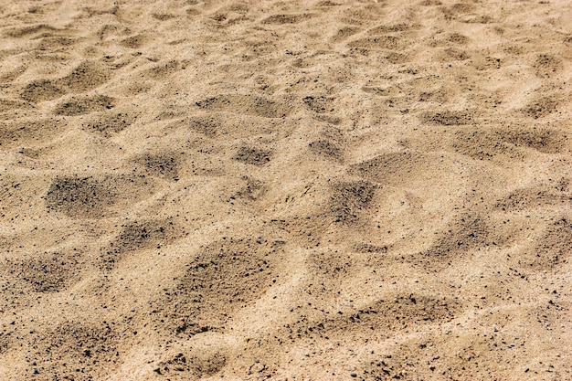 背景のビーチの砂背景のクローズアップとして茶色のビーチの砂のテクスチャ