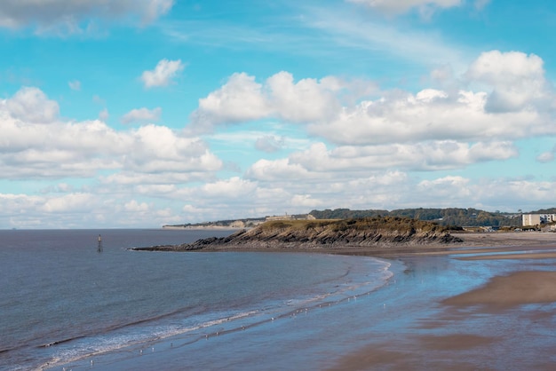 晴れた日のイギリスの砂浜の海と曇った青い空