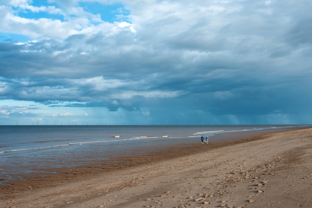 Sand beach, sea and cloudy blue sky in England in sunny day