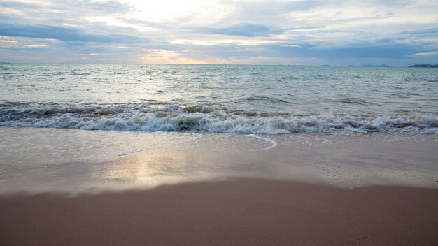 日没の海の波のある砂浜。